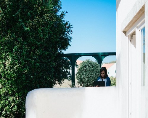 A remote worker taking a short break from a laptop setup, looking outside towards a sunny garden in Puebla