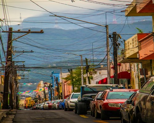 A busy urban avenue in Monterrey with public transport and cars moving during a bright afternoon commute