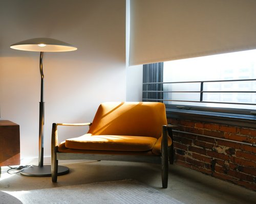 A modern apartment interior with diffuse warm lighting from floor lamps next to a clean reading armchair