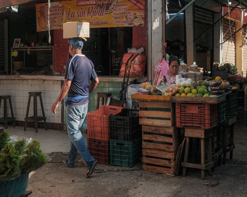 A traditional colorful Mexican neighborhood tianguis market showing fresh seasonal fruits and green vegetables neatly arranged